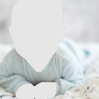 Smiling baby lying on stomach on a bed, wearing a light blue onesie.