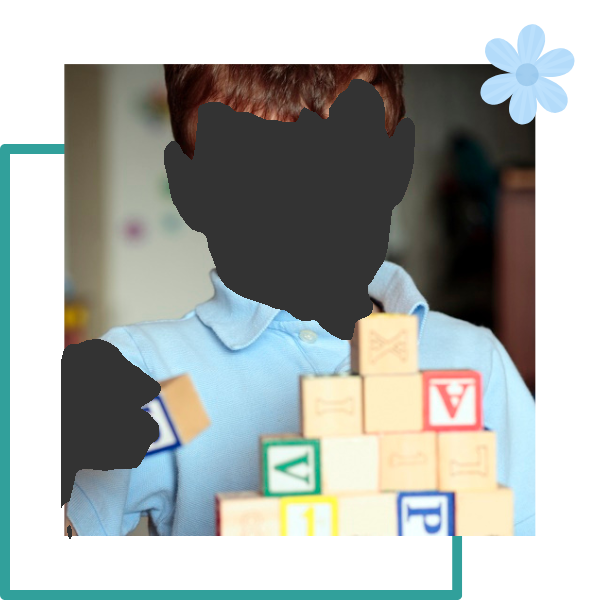 Boy building with alphabet blocks, blue shirt, focused expression.