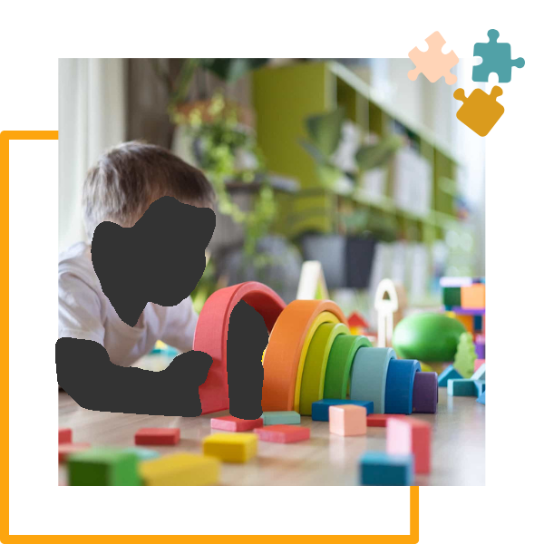 Child playing with a wooden rainbow stacker and colorful blocks on a wooden floor.