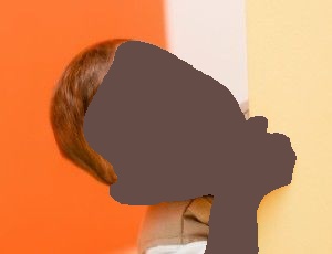 Smiling baby peeking around a yellow wall, orange background.
