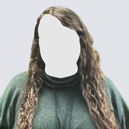 Woman with long, wavy hair and glasses smiles. She wears a green sweater against a light gray background.