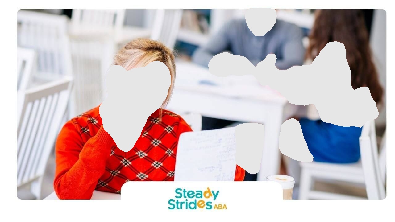 ABA student reviewing notes in a classroom, looking thoughtful while studying with classmates.