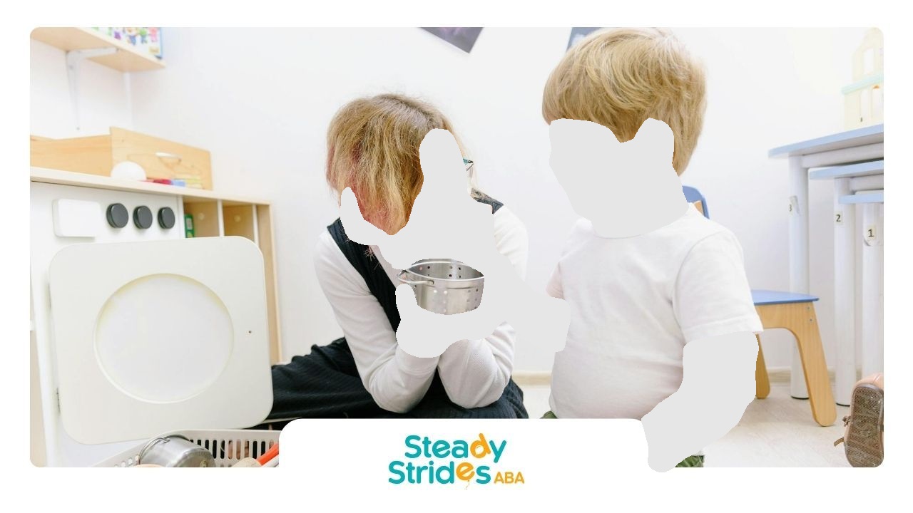 Woman and child looking into a metal bowl in a playroom. Woman is holding bowl. Child wearing a white t-shirt.