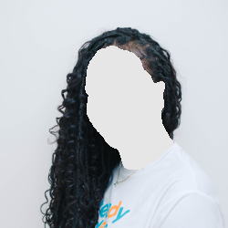 Woman with long, black, curly hair smiles and looks toward the camera. She wears a white shirt against a white backdrop.