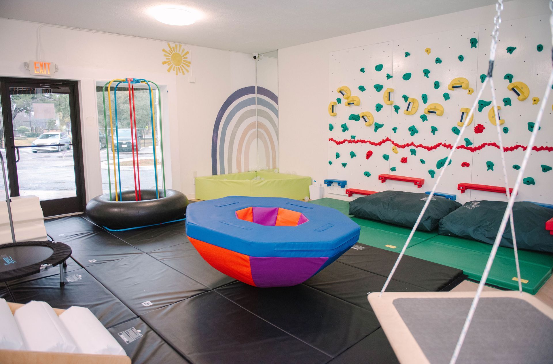 Playroom with climbing wall, swings, and colorful soft play equipment.