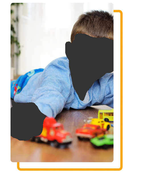 Boy lying on floor, playing with toy cars.