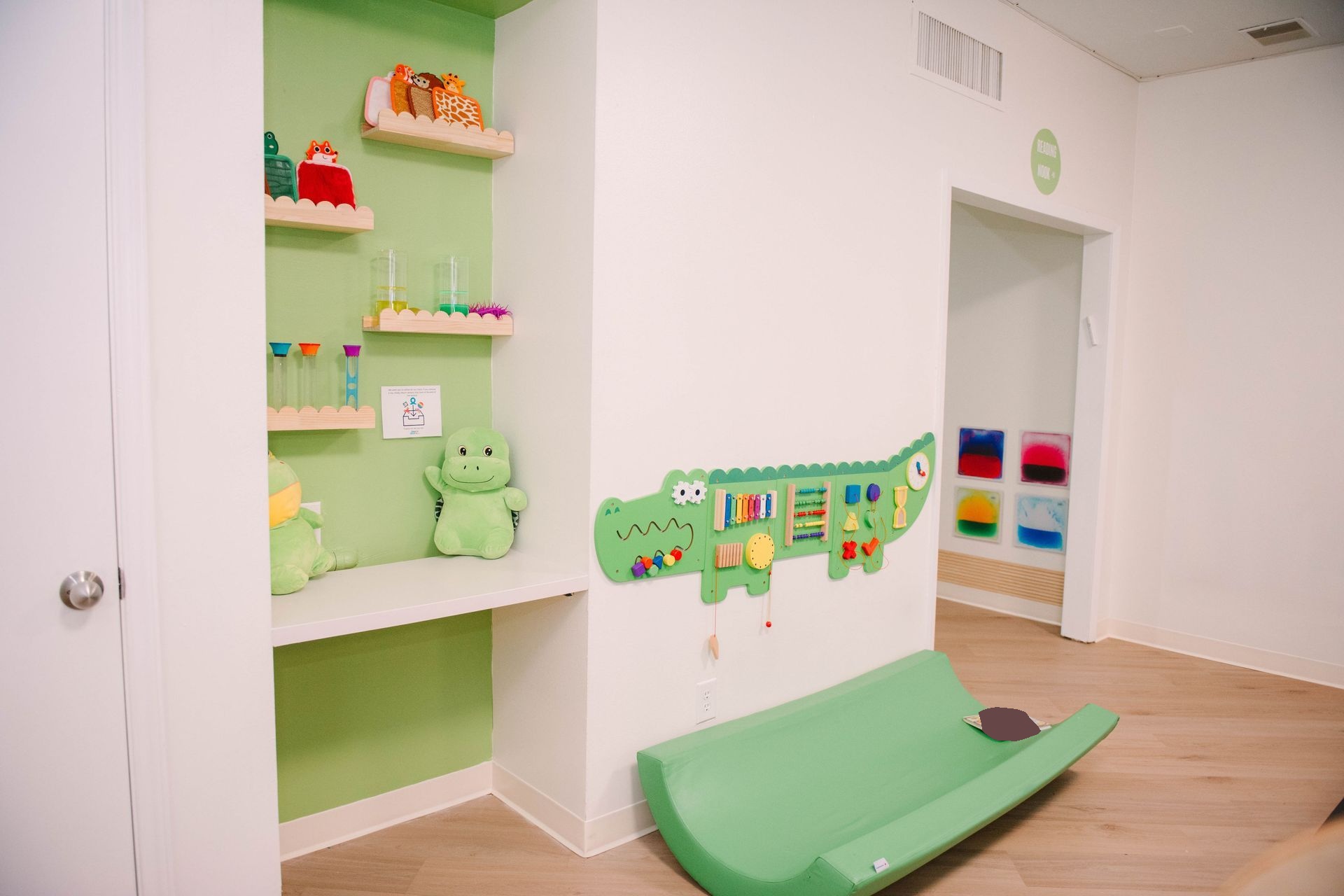A child 's room with a green couch and a green crocodile on the wall.