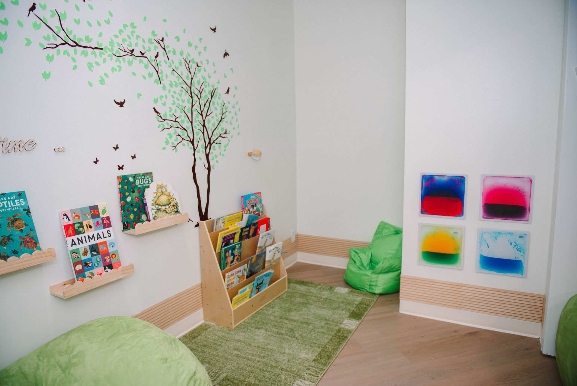 A room with a bookshelf , bean bag chairs , and paintings on the wall.