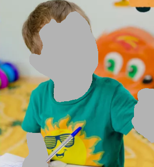 Smiling child in a green shirt with a sun design, holding a pen.