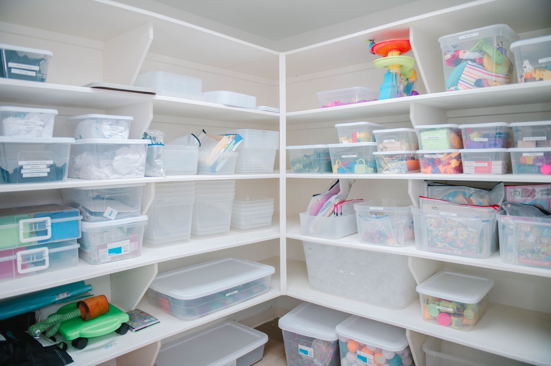 A pantry filled with lots of plastic bins and shelves.