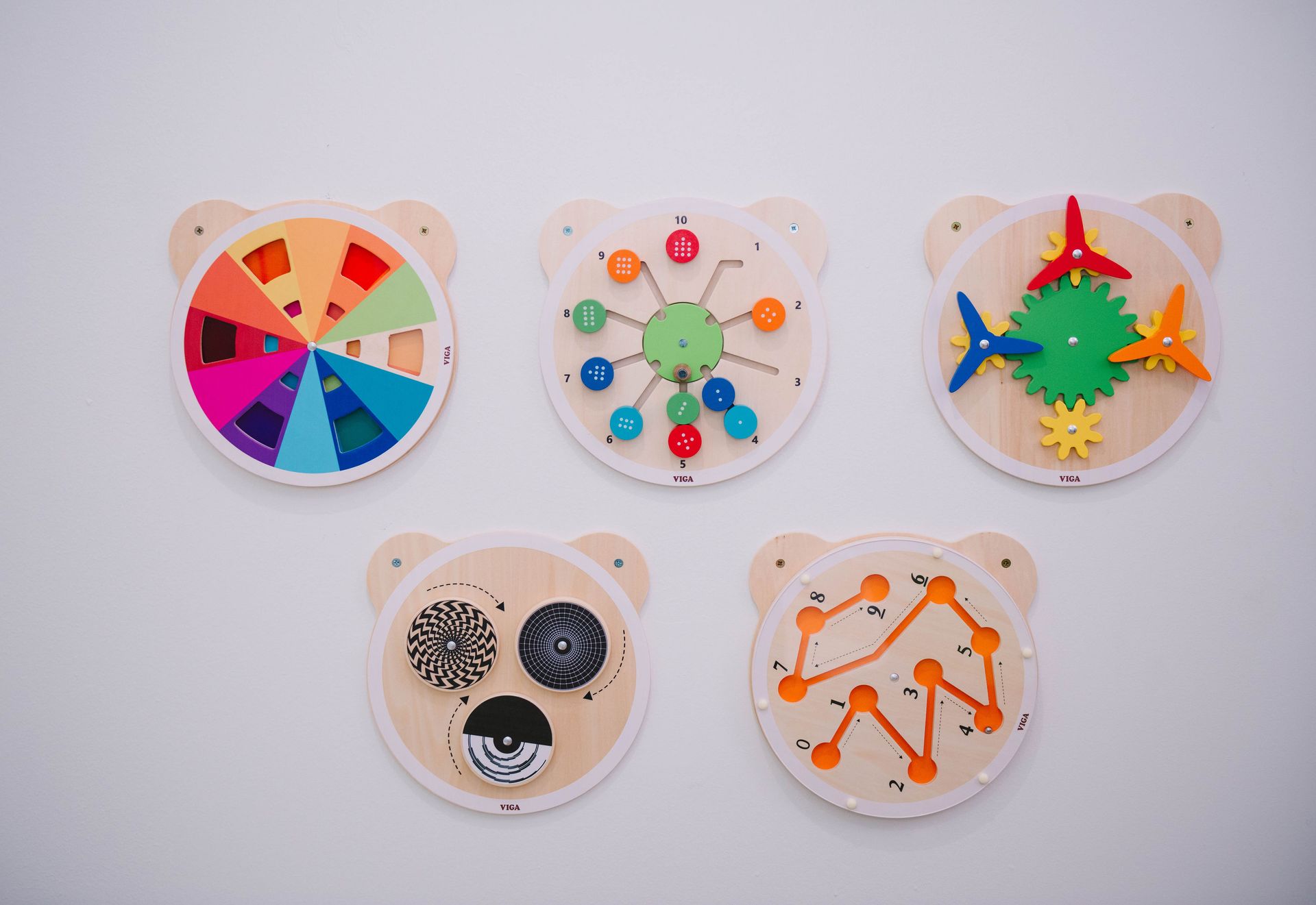 A group of wooden toys are sitting on a white wall.