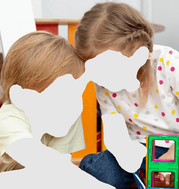 Two children playing with colorful magnetic blocks, indoors.