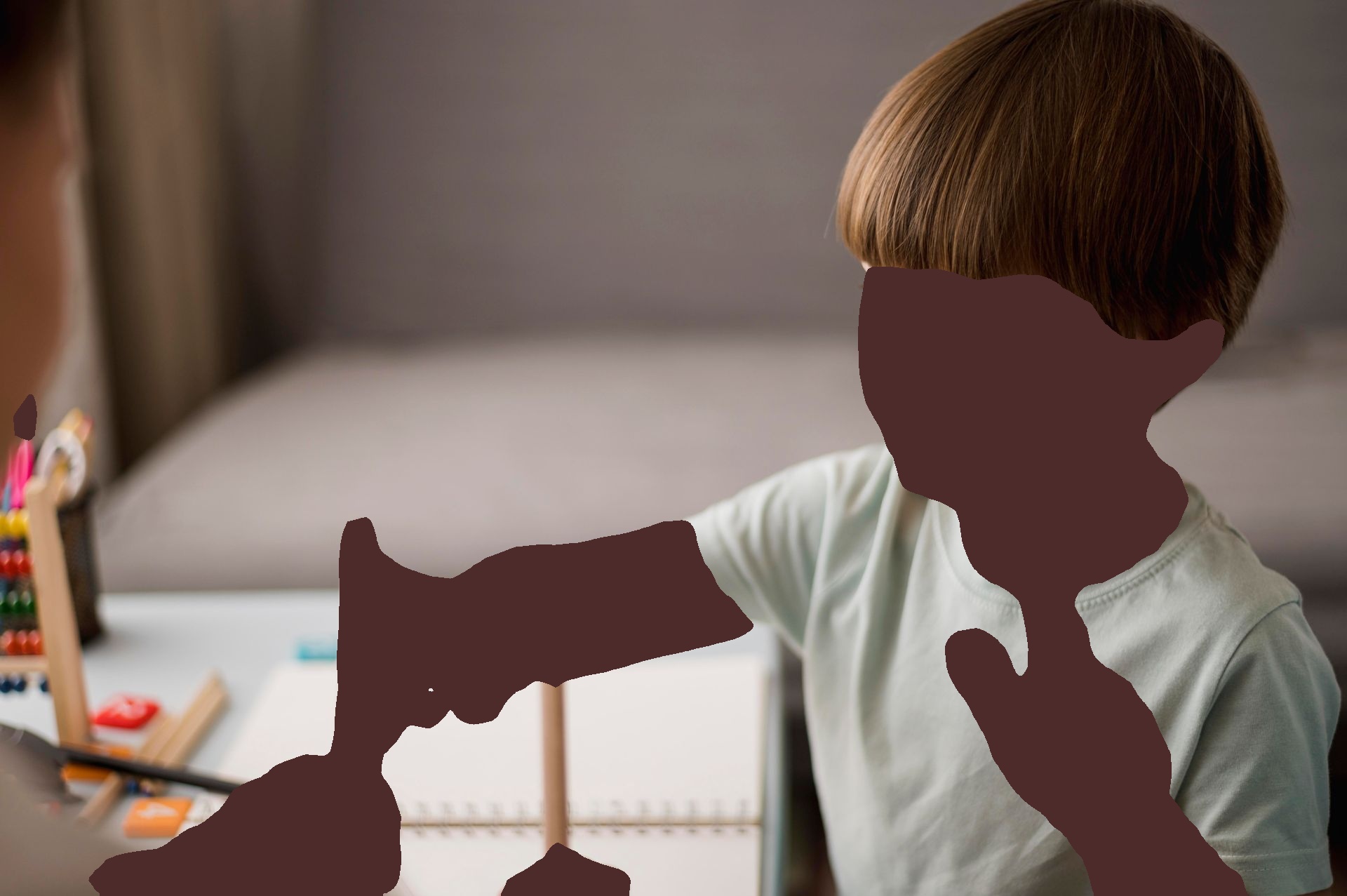 Boy points at pencils while counting with person in home setting.