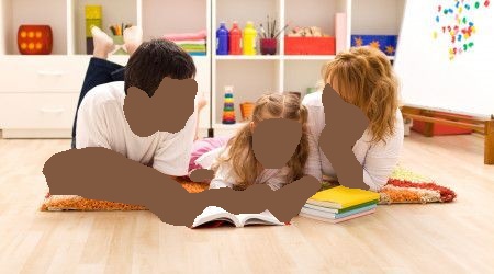 Family reading together on a rug in a playroom, looking at a book.