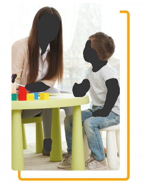 A woman sitting at a table talking to a young boy